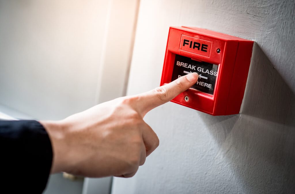 Hand pressing fire alarm button